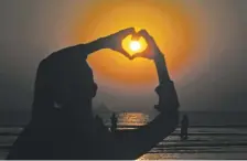  ?? FAREED KHAN/ASSOCIATED PRESS ?? A boy makes a heart sign while the last sunset of 2020 hangs over the Pakistan capital of Karachi on New Year’s Eve on Thursday.