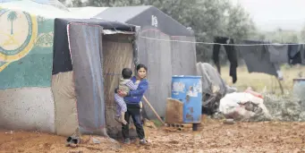  ??  ?? Syrian children who fled airstrikes in their hometown are pictured near tents at an informal camp for displaced people where they live with their families, in Idlib, Jan. 7, 2020.