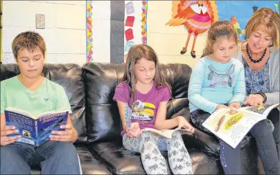  ?? ERIC MCCARTHY/JOURNAL PIONEER ?? Ellerslie Elementary School librarian, Janet Doran, looks on as Grade 1 student. Miley Rodd reads from a library book. Also checking out some of the library’s books are Grade 6 student Jaxon Ballum and Grade 4 student Alice MacKendric­k. The school is...