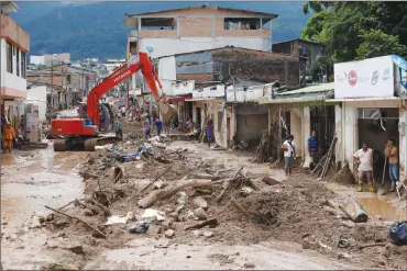  ?? Associated Press photo ?? A backhoe removes debris and mud from a street in Mocoa, Colombia, Sunday. Colombia's President Juan Manuel Santos, who has declared Mocoa a disaster area, said that at least 207 were killed in weekend floods, but that the death toll was changing...