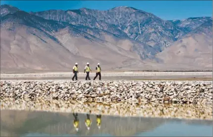  ?? Al Seib
Los Angeles Times ?? OFFICIALS FROM the Los Angeles Department of Water and Power walk along a roadway built in the Owens Lake bed.