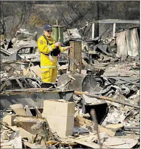  ?? AP/ERIC RISBERG ?? A California fire official looks over the devastatio­n Wednesday at the Journey’s End Mobile Home Park in Santa Rosa, Calif., where a wildfire roared through on Monday.