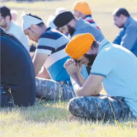  ?? Pictures: MIKE BATTERHAM ?? Close friend Gurpreet Singh (orange Turban) bows his head during a memorial for Ravneet Singh who drowned at Duranbah on Christmas Day and (below) friends survey the scene where their mate died.
