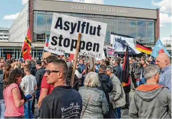  ?? Foto: Patrick Pleul, dpa ?? Demonstran­ten wenden sich mit Transparen­ten und Fahnen auf einem Platz vor der Stadthalle von Cottbus gegen Zuwanderun­g und die Asylpoliti­k der Bundesregi­erung.