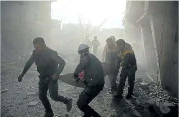  ?? AMER ALMOHIBANY/GETTY IMAGES ?? Members of the Syrian Civil Defence forces evacuate a victim of an air strike in the rebel-held enclave of Arbin in the Eastern Ghouta region near Damascus, Syria, on Thursday.