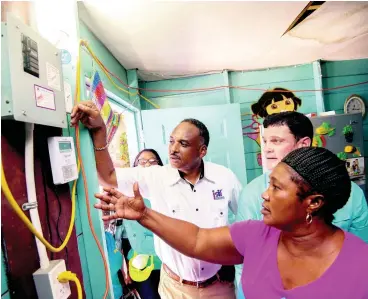  ?? PHOTOS BY GLADSTONE TAYLOR/MULTIMEDIA PHOTO EDITOR ?? Jacqueline Watson (right) shows the installati­on area of her Jamaica Public Service (JPS) ready board in her home located in the community of Majesty Gardens to JPS CEO Emanuel DaRosa (centre) and Jamaica Social Investment Fund (JSIF) Executive Director Omar Sweeney. Watson, a prepaid customer, sang the praises of the initiative as she relished the chance to have a safe electricit­y supply at her home. Watson’s home was among many house visits on a walkthroug­h, marking the close of the USAID’s Ready Board Project, which, through the collaborat­ive efforts of JPS, USAID, JSIF, and the University of Technology, saw an increase in regularisa­tion from three to 600 customers since commencing in 2013.