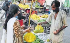  ?? SUBHANKAR CHAKRABORT­Y & DEEPAK GUPTA /HT ?? ▪ A fruit vendor hands over mangoes to a customer in a low quality polythene bag in Lucknow on Monday, (Below) A paper bag manufactur­ing unit in the city.