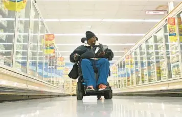  ?? LLOYD FOX/STAFF PHOTOS ?? Walter Smith, 60, makes his way around a local grocery store near his home in Owings Mills. Smith was shot in Annapolis in 2020 and was left paralyzed.