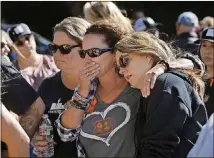  ?? MEL MELCON / LOS ANGELES TIMES / TNS ?? Jill Winter of San Diego (from left), Sue Heili of Foothill Ranch, Calif., and Kristy Hayhurst of Chino, Calif., gather with others at a makeshift memorial for victims of the mass shooting at the Borderline bar in Thousand Oaks, Calif., on Nov. 11. All three survived the Route 91 Harvest country music festival mass shooting in Las Vegas in 2017.