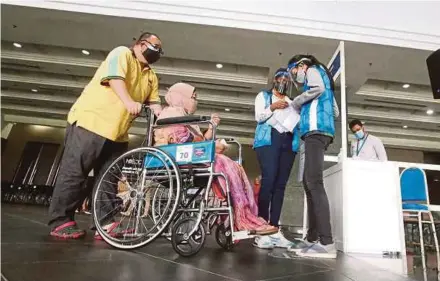 ?? FILE PIC ?? Volunteers helping a disabled person at a vaccinatio­n centre in Kuala Lumpur recently.