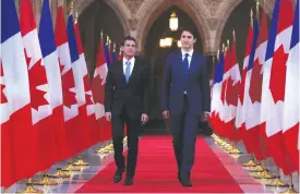  ??  ?? OTTAWA: French Prime Minister Manuel Valls (L) and Canadian Prime Minister Justin Trudeau walk down the hall of honor on Parliament Hill. — AFP