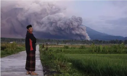  ?? Photograph: AP ?? A man looks on as Mount Semeru releases volcanic materials during an eruption on Sunday.