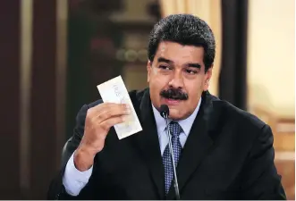  ?? VENEZUELAN PRESIDENCY/AFP ?? Venezuelan President Nicolas Maduro displays a new banknote on Friday. The official rate for the country’s currency will go from about 285,000 per dollar to 6 million.