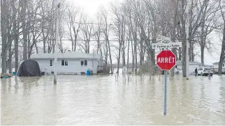  ?? GRAHAM HUGHES/THE CANADIAN PRESS ?? This intersecti­on in Rigaud, west of Montreal, was completely submerged Thursday. The town is providing temporary housing, though some residents are defying an evacuation order.
