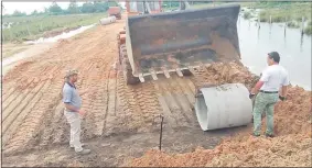  ??  ?? Operarios del Ministerio de Obras Públicas colocan tubos de hormigón para el escurrimie­nto del agua.