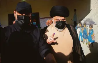  ?? Anmar Khalil / Associated Press ?? Populist Shiite cleric Muqtada al-Sadr (right) displays his ink-stained finger after voting Sunday in Najaf. Candidates allied with his movement appear to have gained seats.