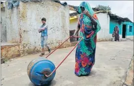  ??  ?? A woman uses a ‘Water Wheel’ — a drum that doubles up as a wheel, attached to two handles — to take water to her home in Patharihav­eli village of Madhya Pradesh’s Vidisha district. MUJEEB FARUQUI/HT