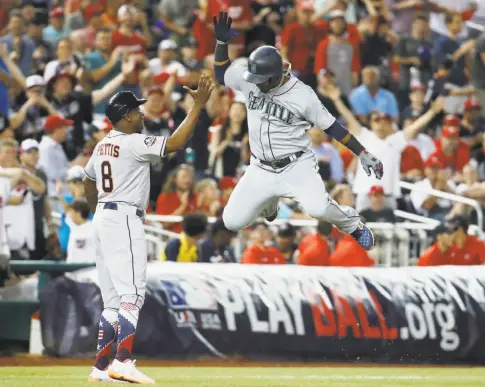 ?? Alex Brandon / Associated Press ?? Mariners shortstop Jean Segura celebrates his three-run homer with third-base coach Gary Pettis of the Astros during the eighth inning.