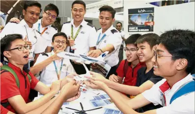  ??  ?? Life full of action: Dilog’s Training and Services volunteer Imran Hanafi Rozahar (fourth from right) pointing out the different parts of an aeroplane to visitors at the booth.