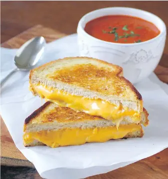  ??  ?? This tangy, easily prepared tomato soup is served with a golden, grilled sandwich containing three types of cheese.