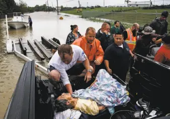  ??  ?? A rescuer moves 92-year-old Paulina Tamirano from a boat to a truck bed as people evacuate from the Savannah Estates neighborho­od as the nearby Addicks Reservoir nears capacity.