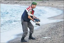  ?? NILUFER DEMIR/DHA/REUTERS ?? A Turkish gendarmeri­e carries a young migrant, who drowned in a failed attempt to sail to the Greek island of Kos, Wednesday in the coastal town of Bodrum, Turkey. At least 11 migrants believed to be Syrians drowned as two boats sank after leaving...