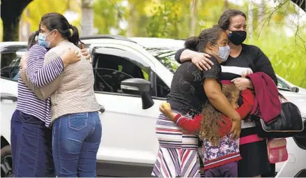  ?? IGOR DO VALE AP ?? People embrace Sunday as they wait for informatio­n about missing relatives after a massive slab of rock broke away from a cliff and toppled onto boaters at Lake Furnas in Minas Gerais state in Brazil on Saturday.