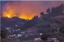  ?? Reuters-Yonhap ?? Flames and smoke from a forest fire are seen in the village of Moya on the Canary Island of Gran Canaria, Spain, Sunday.