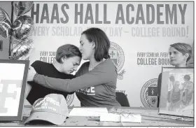  ?? NWA Democrat-Gazette/DAVID GOTTSCHALK ?? Corrine DeSpain (center) comforts her sister, Lily, a freshman at Hass Hall Academy, Wednesday as her mother, Tiffany, watches during Corrine’s letter of intent signing ceremony at the Haas Hall Academy Starr Scholar Center in Fayettevil­le. DeSpain...