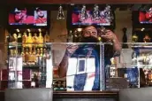  ?? Godofredo A. Vásquez / Staff photograph­er ?? Bartender Daniel Vázquez replaces a safety divider at Picos, which will enforce its own mask rules.