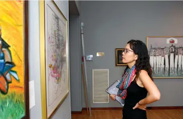  ?? Staff photo by Hunt Mercier ?? ■ Dr. Injeong Yoon examines artwork at the 31st annual Adult Juried Exhibition at Texarkana Regional Arts Center in Texarkana, Texas. The exhibition is featured throughout all three floors with a total of 116 pieces of art on display.