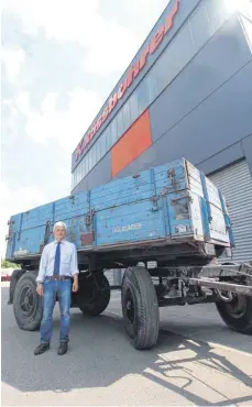  ?? FOTO: REINER SCHICK ?? Der Achstetter Betriebsle­iter Erol Arslan vor einem genau 80 Jahre alten Kässbohrer-Kippanhäng­er, der zum Jubiläum restaurier­t werden soll.