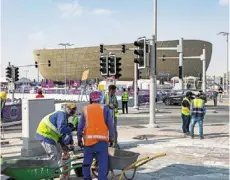  ?? ?? Tireless: migrants working outside Lusail stadium in doha before the World Cup started. — bloomberg