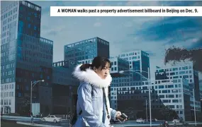  ??  ?? A WOMAN walks past a property advertisem­ent billboard in Beijing on Dec. 9.