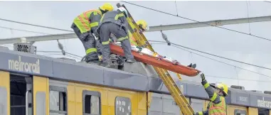  ?? PICTURE: HENK KRUGER ?? KILLED: Rescue workers remove the body of a schoolboy who was electrocut­ed while train-surfing close to Philippi station.