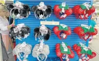  ??  ?? Magic Kingdom shoppers look over holiday-themed headbands, which come in furry, shiny and plaid varieties this season.