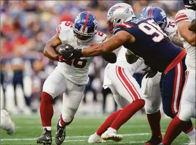  ?? Charles Krupa / Associated Press ?? Giants running back Saquon Barkley runs with the ball as Patriots defensive tackle Carl Davis Jr. defends during the first half on Thursday in Foxborough, Mass.