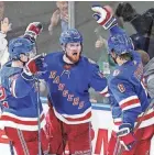  ?? FRANK FRANKLIN II/AP ?? The Rangers’ Alexis Lafreniere­m, middle, celebrates with teammates Filip Chytil, left, and Jacob Trouba, right, after scoring a goal against the Penguins Wednesday in New York.
