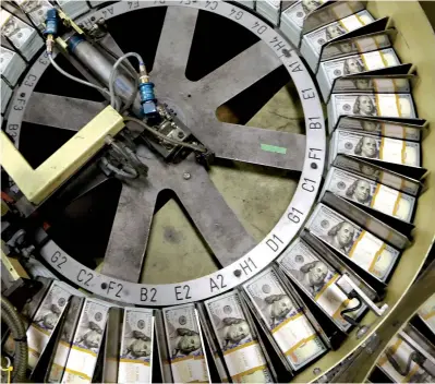  ?? Associated
Press file photo ?? ABOVE: Freshly cut stacks of $100 bills make their way down the line at the Bureau of Engraving and Printing Western Currency Facility in Fort Worth, Texas. After several years of increasing the meager interest they paid on savings accounts and certificat­es of deposit, banks are starting to trim their offerings to savers. The declines are slight, usually less than 0.25 of a percentage point, but the trend
is certain to continue for at least the next six months to a year, experts
say.