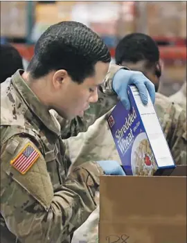  ?? Rich Pedroncell­i Associated Press ?? PFC. GRANT MOCK and other California National Guard troops helped make up for the Sacramento Food Bank’s shortage of volunteers amid heavy demand.