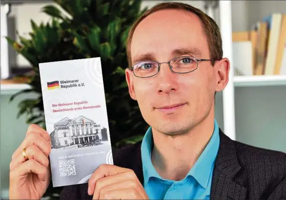  ??  ?? Stephan Zänker vom Verein „Weimarer Republik e. V.“mit einem Flyer zu einer Wanderauss­tellung, die seit reichlich einem Jahr durch Deutschlan­d tourt. Foto: Hanno Müller