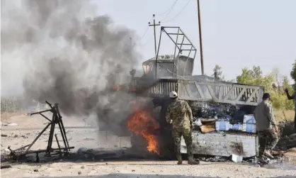  ??  ?? Popular Mobilisati­on Forces members stand by a burning truck after a drone attack near border crossing. Photograph: AP