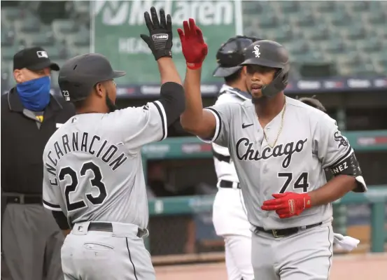  ?? GETTY IMAGES ?? The Sox’ Eloy Jimenez gets a high-five from teammate Edwin Encarnacio­n after his three-run home run in the first inning Tuesday against the Tigers at Comerica Park.