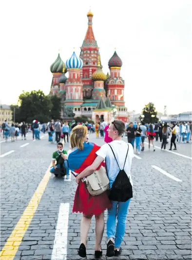  ?? FRANCK FIFE / AFP / GETTY IMAGES ?? Lovers leisurely stroll in front of Saint Basil’s Cathedral in Red Square in Moscow this week during the World Cup.
