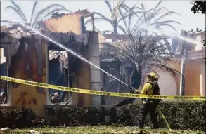  ?? Mario Tama / Getty Images ?? A firefighte­r works to put out hotspots at one of over 20 homes destroyed by the Coastal fire on Thursday in Laguna Niguel, California. The brush fire was fueled by windy and dry conditions amid California’s severe drought, which has been compounded by climate change.