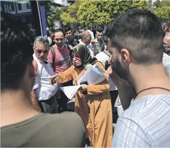  ?? AFP ?? An official in Esenyurt, Istanbul, reads names as Syrian refugees prepare to board a bus to Syria. The municipali­ty provides the bus service for refugees willing to go back home