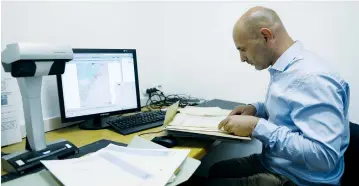  ?? (Ronen Zvulun/Reuters) ?? LIOR YAVNE, founder of and director of the Israeli NGO Akevot, reads declassifi­ed documents at the Central Zionist Archives in Jerusalem last month.