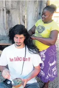  ??  ?? Acting Colonel Marcia Douglas of the Charles Town Maroons braiding the hair of Taino Cuyo Arieto of New York.