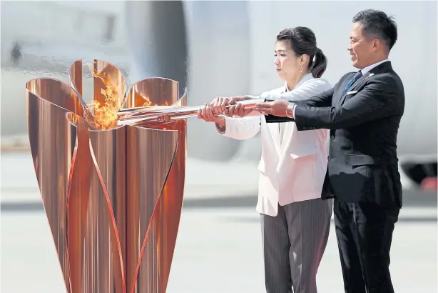  ?? REUTERS ?? Three-time Olympic judo champions Tadahiro Nomura, right, and Saori Yoshida light the Olympic flame at a cauldron during a ceremony at the Japanese Air Self-Defence Force’s Matsushima base yesterday.