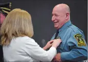  ?? SARAH GORDON/THE DAY ?? Ledyard Police Chaplain the Rev. Robert Petriel laughs as he is pinned by his wife, Lisa Petriel, during a Law Enforcemen­t Awards and Appreciati­on Day event Sunday.